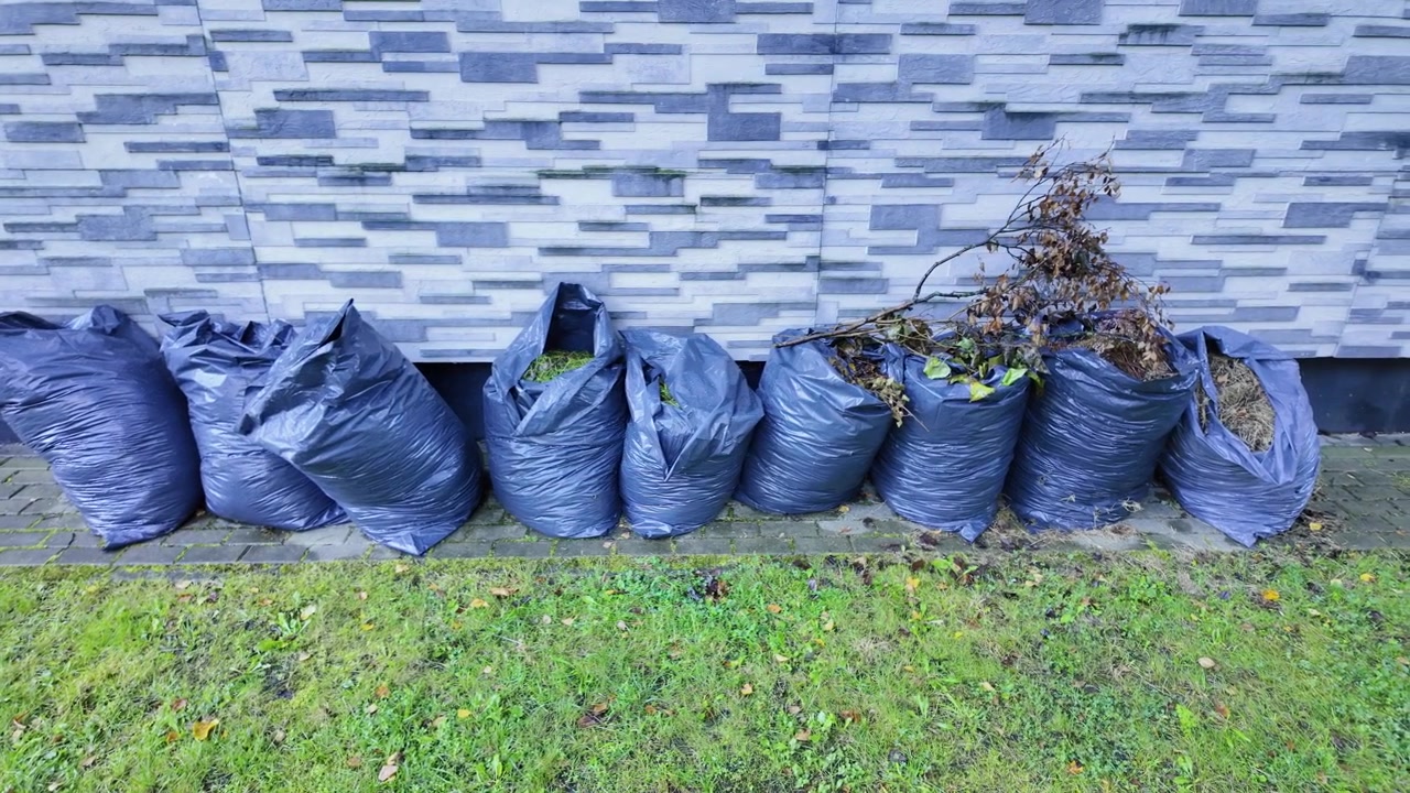 Orderly yard waste collection beside tiled wall captures calm autumn routine day