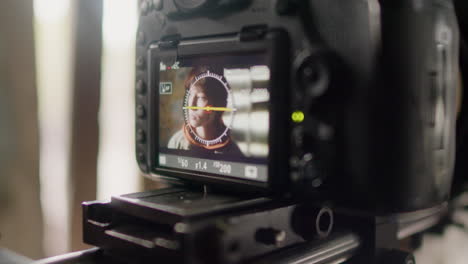 close up view of a camera recording a scene of a redhead girl in a ruined building