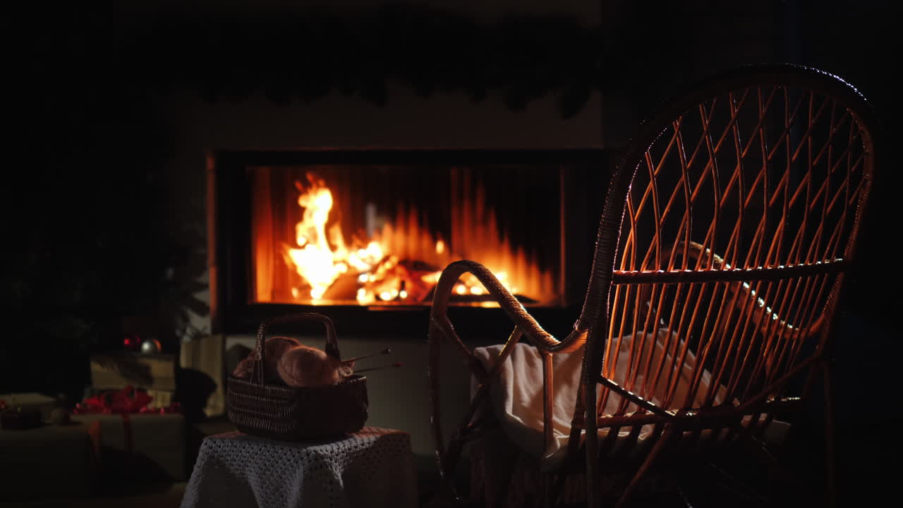 빈 흔들의자가 바느질 세트 옆 벽난로 옆에서 흔들린다