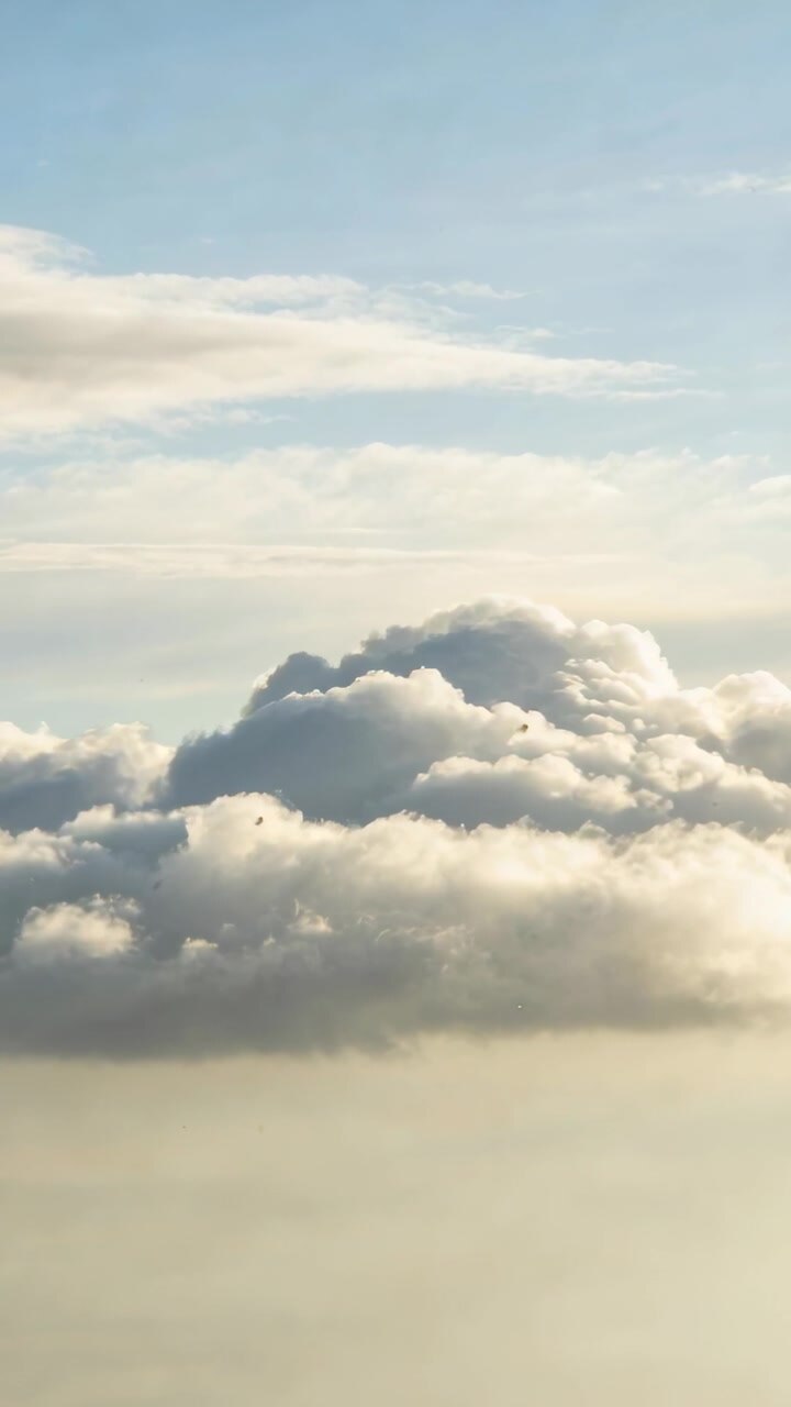 Vertical video: Drifting viewpoint moving toward cumulus over cloud deck, revealing sunlit texture
