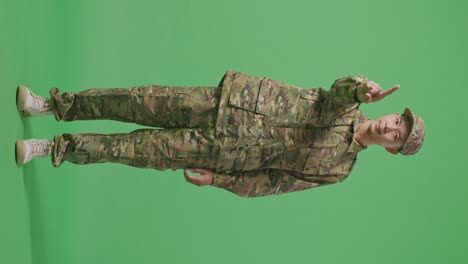 full body of asian man soldier pointing at you and disapproving with no index finger sign while standing in the green screen background studio