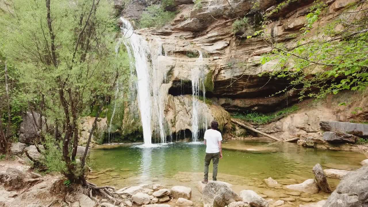 casual joven sano admirando la cascada calmante en el paseo de ocio en la naturaleza