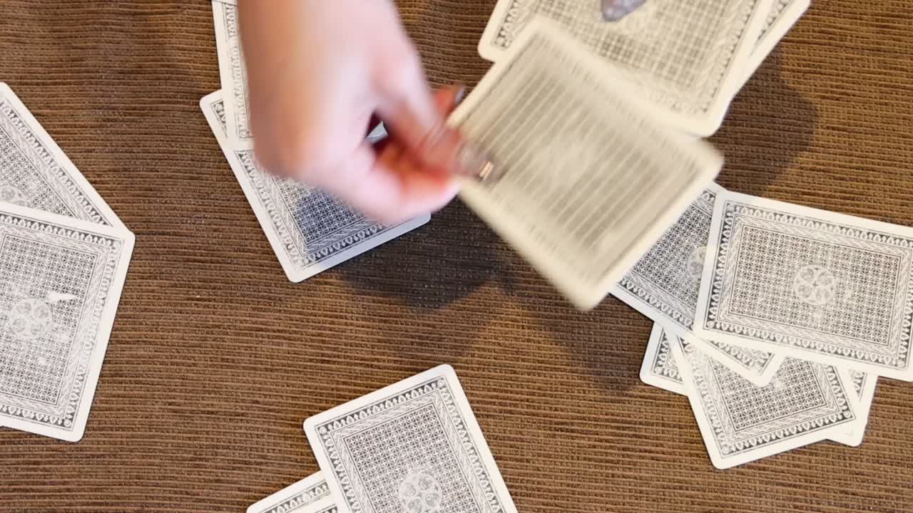 Close-up of hands skillfully arranging playing cards on a textured brown surface.