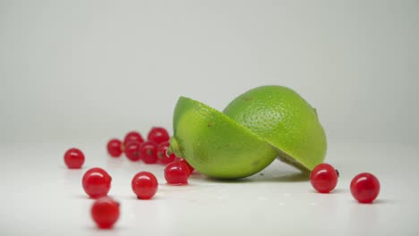 Köstliche-Rote-Johannisbeeren-Und-Geschnittene-Limette-Auf-Dem-Drehteller-Mit-Reinweißem-Hintergrund---Nahaufnahme