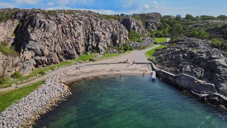 Vista-Aérea-De-La-Gente-En-La-Playa-De-Langevik-Con-Costa-Rocosa-Y-Acantilado-En-Lysekil,-Suecia