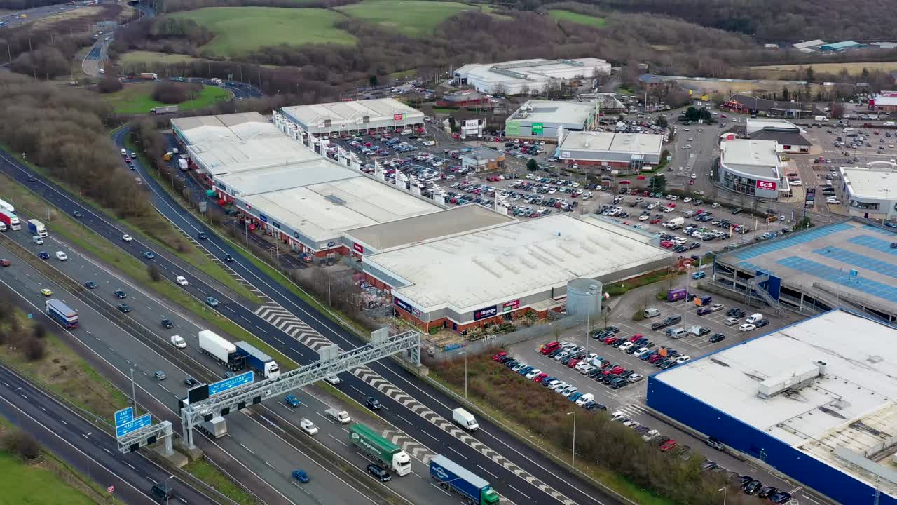 Aerial footage of the M1, M62 and M62 motorway located near the town of Birstall near the shopping complex with ikea showing the typical British road systems drone footage.