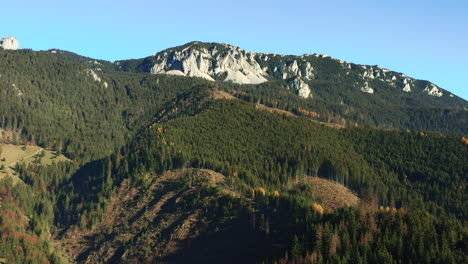 Aerial-parallax-orbiting-limestone-cliff-over-forest,-Hasmas-Mountains,-Romania