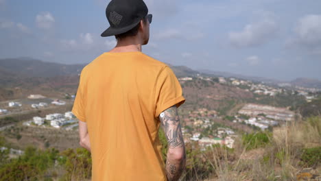 young man with cap on mountain having a glucose level sensor on tattooed arm to control diabetics blood sugar level