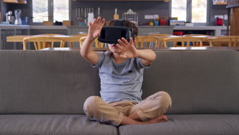 boy sitting on sofa wearing virtual reality headset