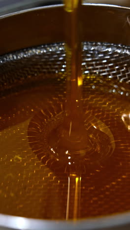 organic fresh honey pouring on the metal sieve. filtering honey right after extraction. close up. vertical video