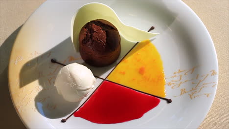 elegante postre de fondante de chocolate con helado y salsas de frutas