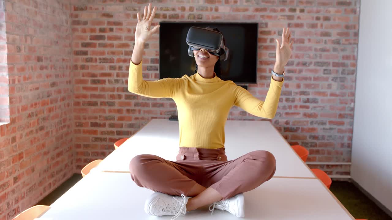 African american casual businesswoman using vr headset sitting on table in meeting room, slow motion