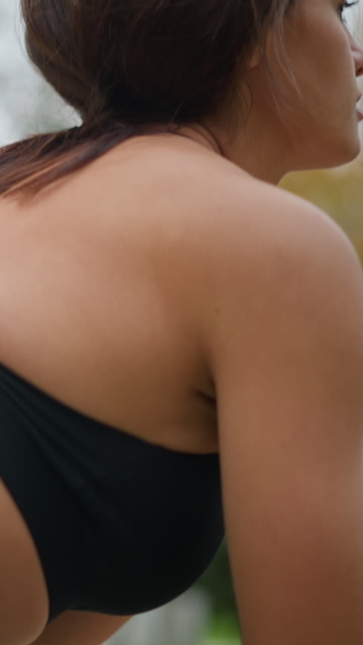 Close-up view of young woman in black tight leggings and neck singlet performing squats outdoors in a park, focusing on fitness and strength training in a natural environment