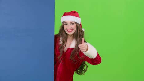 woman in santa claus costume behind a blue board on a green screen