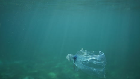 bolsa de plástico flotando bajo el agua con reflejos de luz