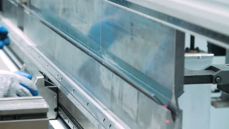 worker bending metal plate on industrial machine. operator working with blank