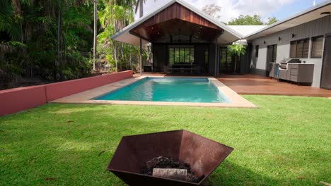 outdoor space with a cozy fireplace, pool, and lush greenery, designed for relaxing and outdoor entertainment.