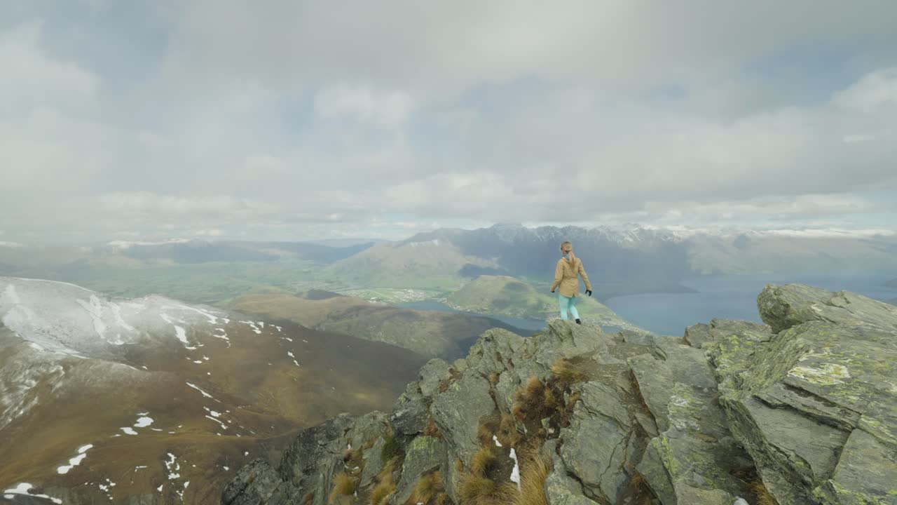 mujer corriendo hacia el borde de la roca de la cumbre de ben lomond con una vista increíble