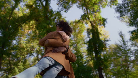 gentle father embracing daughter spinning kid in sunny park. loving parent hugs.