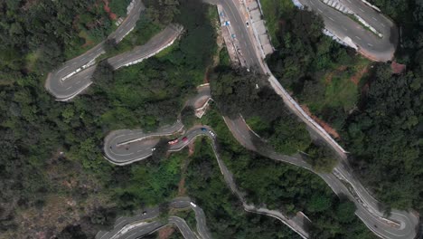 hairpin bends in yercaud, india covered with endless vast green forest with trees growing rapidly vehicles passing on the road