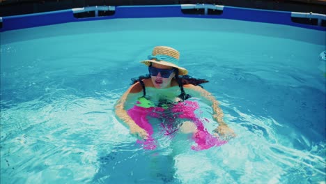 young woman enjoying summer day in swimming pool with colorful float and sun hat