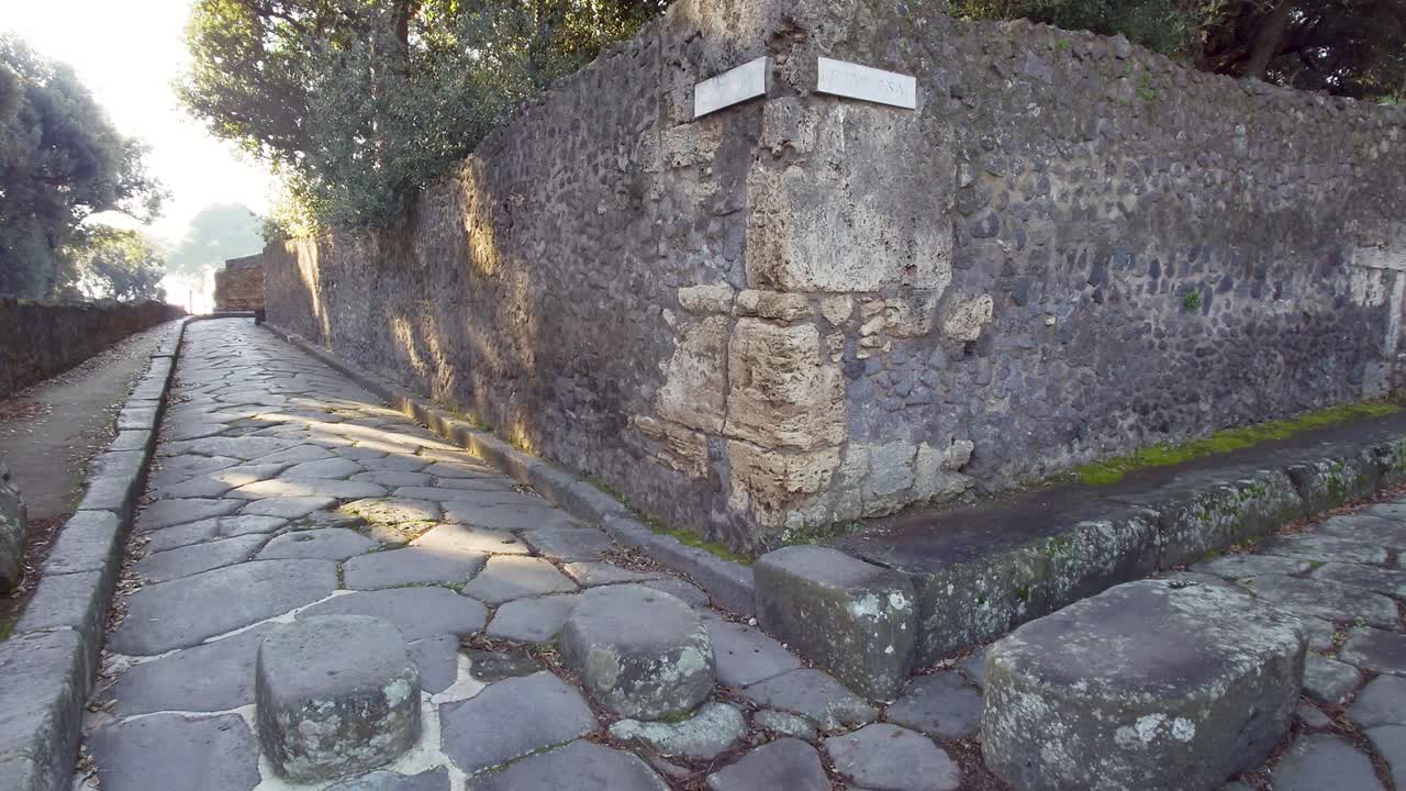Paved street in ancient Pompeii, Italy. Road on the right called Vicolo delle Pareti Rosse - Panning shot