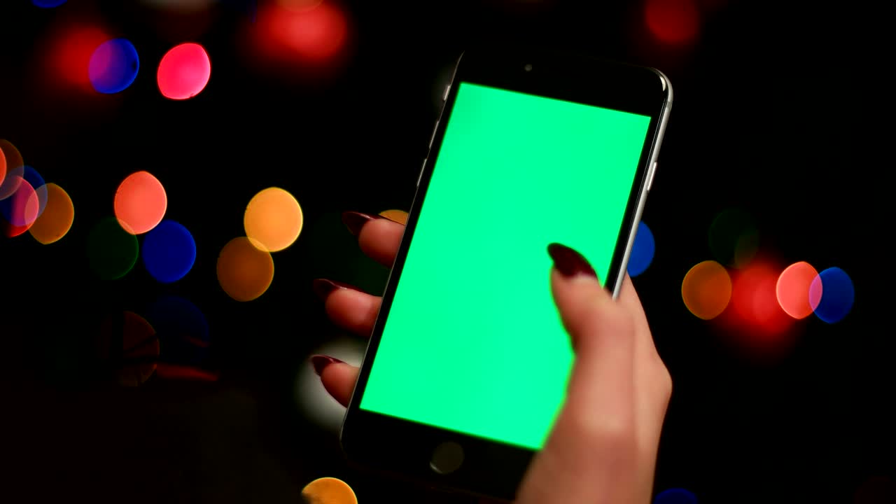 스마트 폰을 사용하는 여성의 손은 그린 스크린과 함께 장미 bokeh 배경. 가까이. 크로마 키.