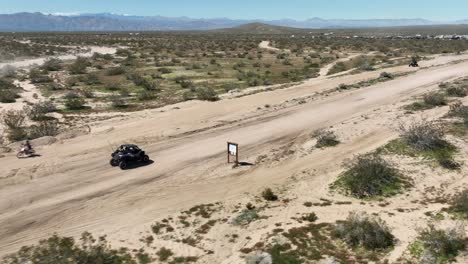 Following-an-all-terrain-vehicle-along-a-Mojave-Desert-dirt-road---aerial-tracking