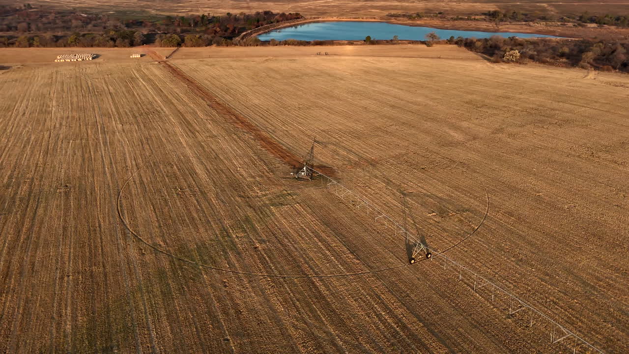 Drone orbit shot around center-pivot irrigation system on dry farm land