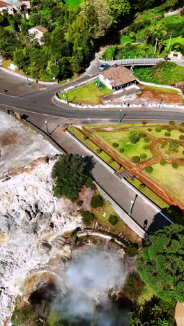 green park with geysers near the roads in the city. beautiful nature of the azorean islands from top. vertical video.