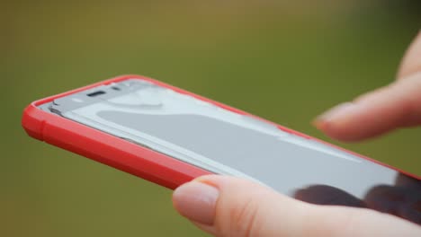 broken red phone screen. close up of woman's hand touching red mobile phone with blurred yellow green background, by sending sms messages.