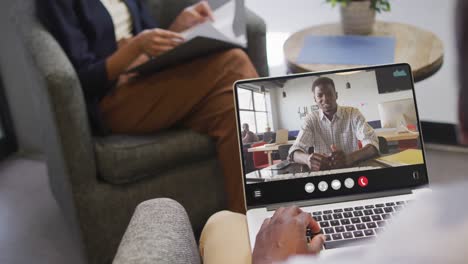 Hombre-Afroamericano-Usando-Una-Computadora-Portátil-Para-Videollamadas,-Con-Un-Colega-De-Negocios-En-La-Pantalla