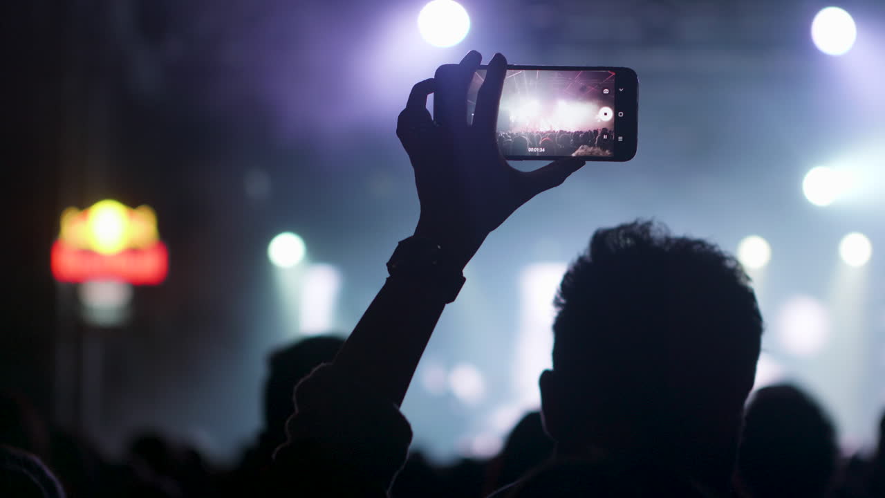 Pubblico a un concerto che filma con lo smartphone