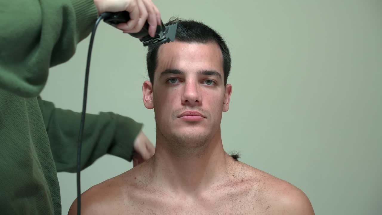 Woman Cutting Man's Hair Using Electric Razor - Close Up