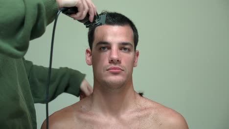 woman cutting man's hair using electric razor - close up