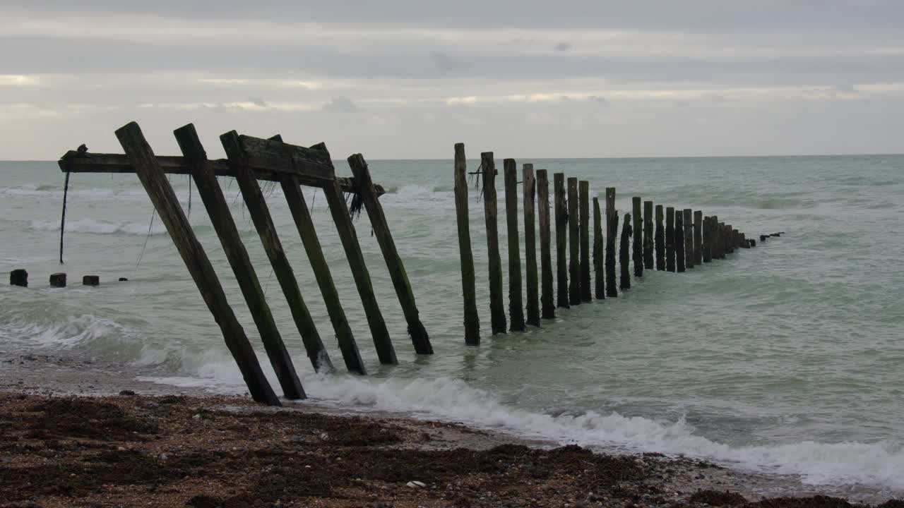 Bredt billede med ødelagte høfder, der strækker sig ud i havet ved Cuckmere Haven strand, ved siden af Seaford Head.
