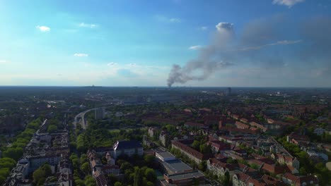 big black smoke rising over berlin, germany, on sunny day with blue sky and some clouds. great aerial view flight panorama overview drone