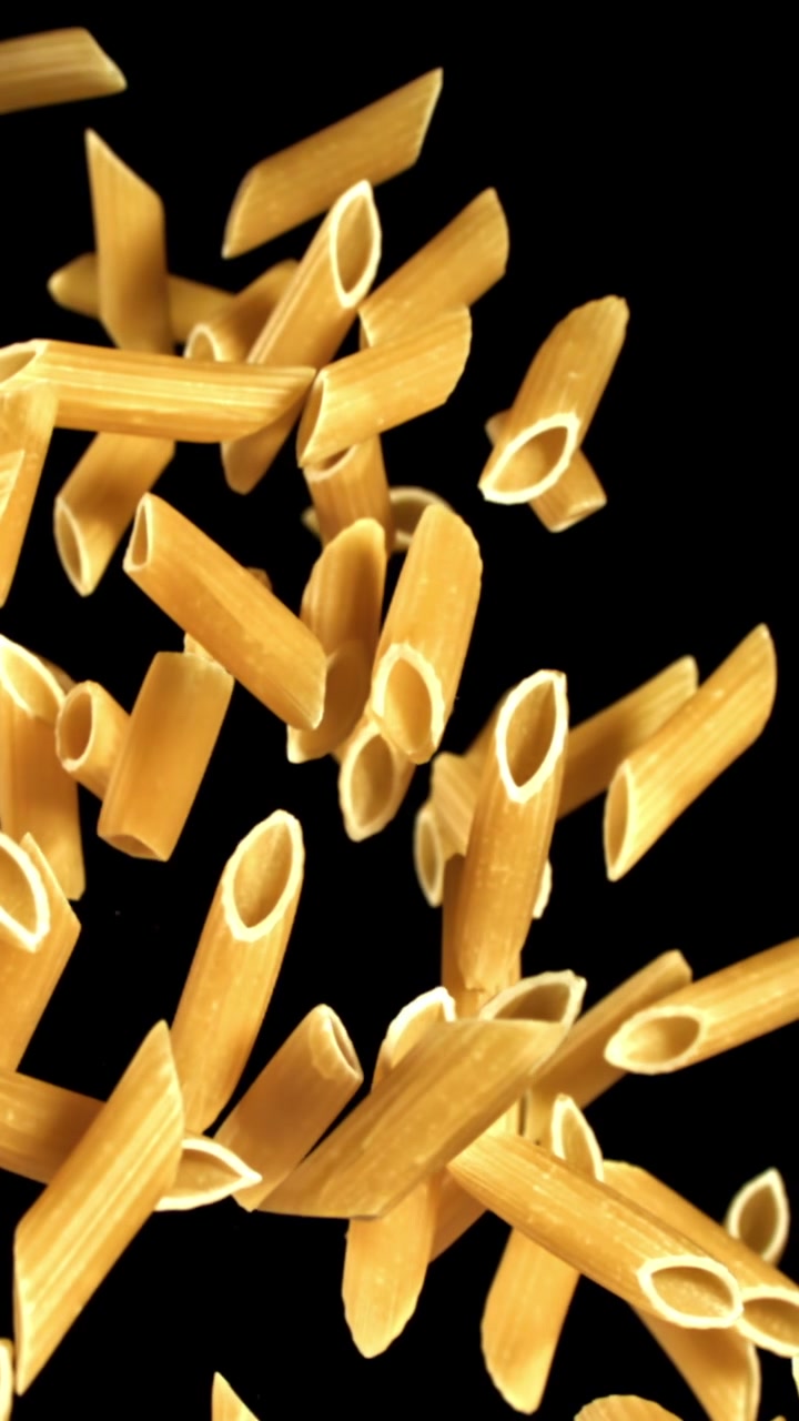 Penne secche che cadono al rallentatore su sfondo nero