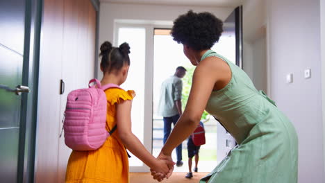 parents at home helping children get ready and leave as family go to school together