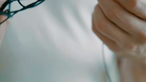 man untangling tangled earbuds, headphone wire tangled