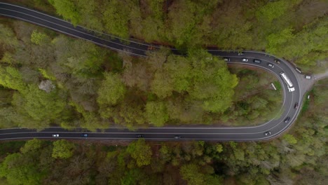 passing cars and truck in a winding road in the mountains in the middle of wooded nature - bird's eye view down