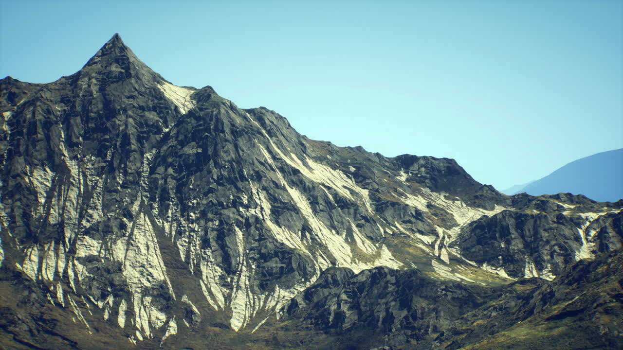 Majestic mountain peak with rugged terrain under clear blue sky at midday
