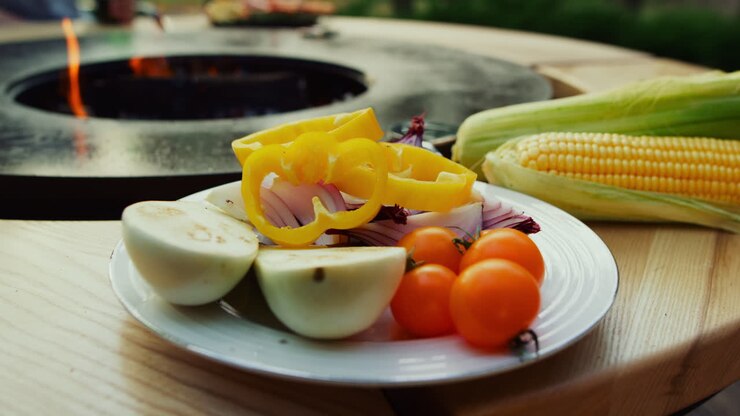 Plato con verduras cerca de la parrilla de barbacoa al aire libre