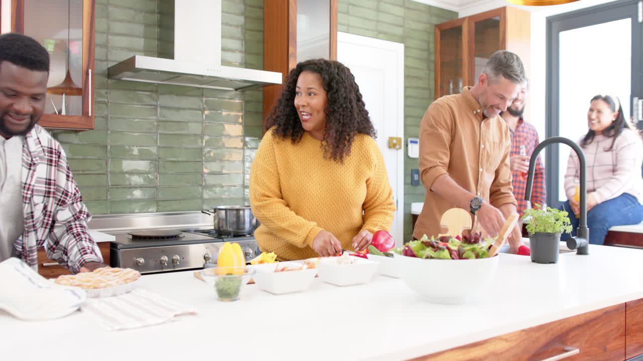 Amigos e amigas diversos e felizes preparando comida juntos na cozinha