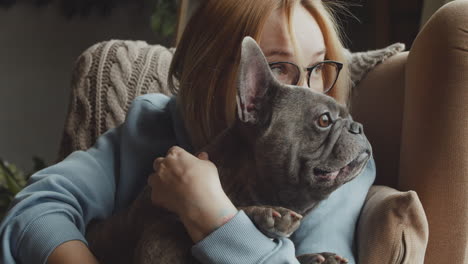 nahaufnahme einer rothaarigen frau, die ihren bulldoggenhund streichelt, während sie zu hause auf dem sofa im wohnzimmer sitzen 4