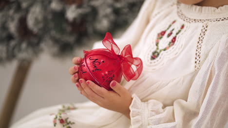 Zeitlupenaufnahme-Eines-Jungen-Mädchens-In-Einem-Weihnachtlich-Verzierten-Weißen-Kleid-Mit-Einer-Roten-Kugel---Nahaufnahme