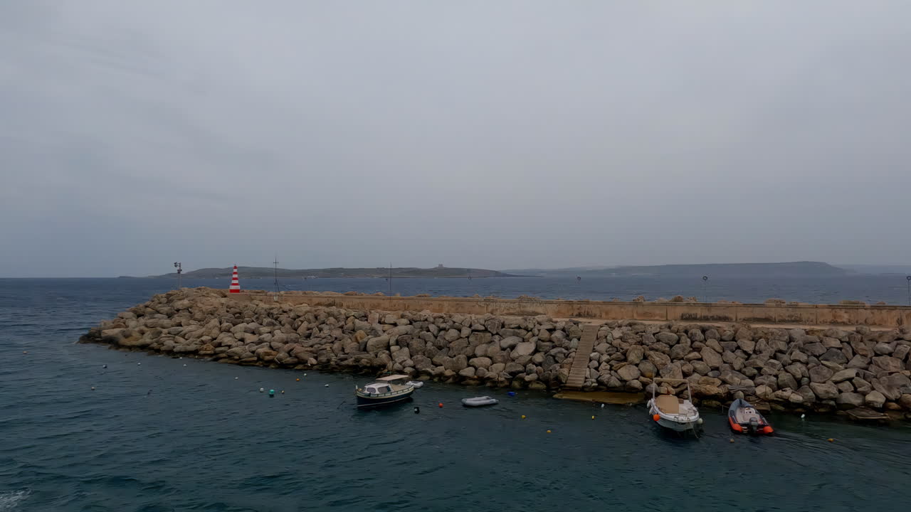 고조 섬 에서 몰타 의 해안 해역 을 내려다보는 mgarr breakwater beacon