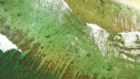 waves crashing into the shoreline at the exotic holiday location of bali captured from the air