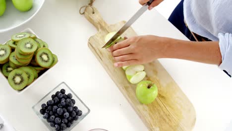 Woman-cutting-green-apple-on-chopping-board