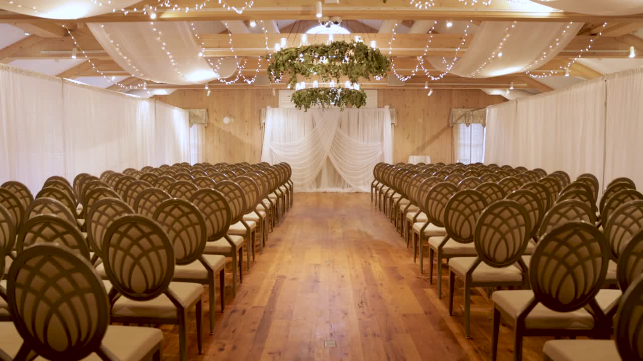 Allestimento elegante e lussuoso per cerimonia di matrimonio al coperto con luci e vegetazione.